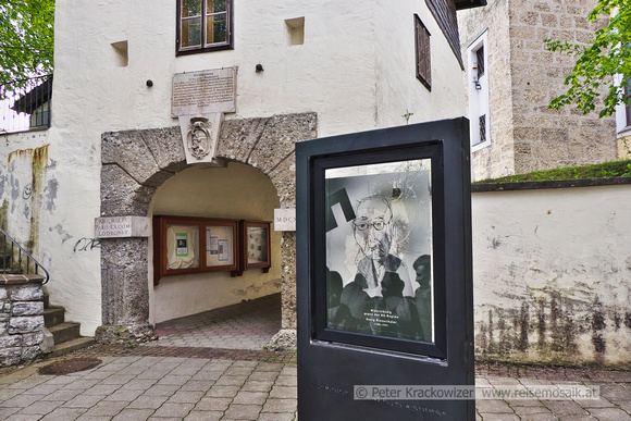 Kunstprojekt Einwurf in Neumarkt am Wallersee vor dem Schanzhäusl, 8. Mai 2022: Hier sieht man eine eingeworfene Scheibe, überklebt mit einer Folie, die Georg Rinnerthaler zeigt, darüber eine Zeichnun